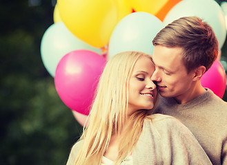 Image showing couple with colorful balloons kissing in the park