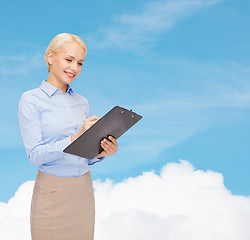 Image showing smiling businesswoman with clipboard and pen