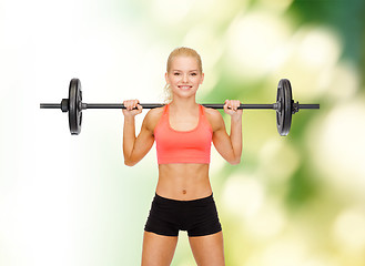 Image showing smiling sporty woman exercising with barbell