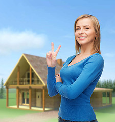 Image showing smiling teenage girl showing v-sign with hand