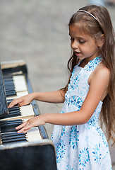 Image showing Little girl playing on a piano