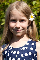 Image showing little girl with camomile flower in long hair 