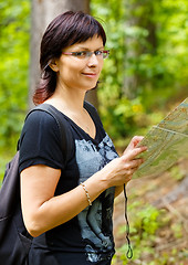 Image showing Lost smilling woman in the countryside holding a map