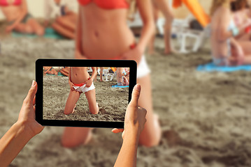 Image showing Woman taking pictures on a tablet Girls on a beach