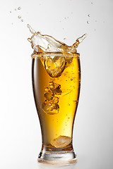 Image showing Ice falling into beer glass with splash isolated