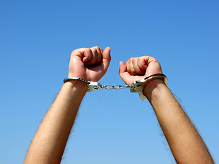 Image showing The hands of the men chained in handcuffs, on a background of th