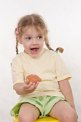 Image showing The three-year girl laughing eating a bun