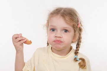 Image showing Three year old girl eating a croissant