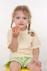 Image showing Girl eating a bun sitting on chair