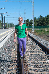 Image showing Young men walking on the rail track