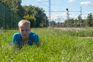 Image showing Young man in blue lying on the green grass