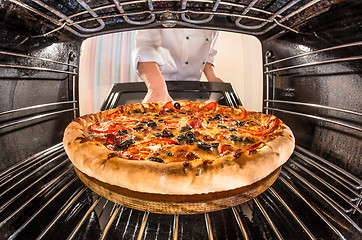 Image showing Chef cooking pizza in the oven.