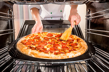 Image showing Chef cooking pizza in the oven.