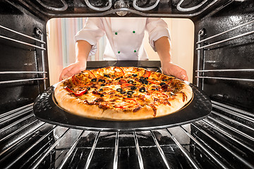 Image showing Chef cooking pizza in the oven.