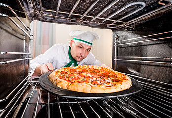 Image showing Chef cooking pizza in the oven.