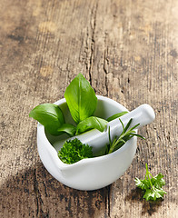 Image showing green herbs in a mortar and pestle