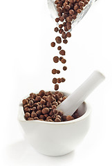 Image showing Black aromatic peppercorns falling into mortar and pestle