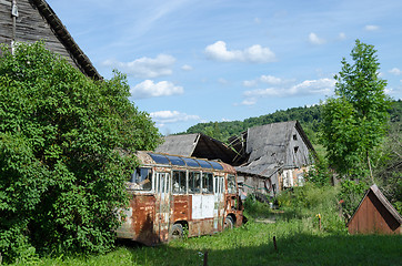 Image showing rusty broken bus stand along country rotten house  