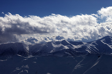 Image showing Evening sunlight mountain with clouds and silhouette of parachut