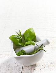 Image showing green herbs in a mortar and pestle