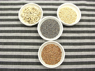 Image showing Four bowl with different seeds on a striped background