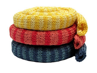 Image showing Three striped reeled up knitting scarfs on white