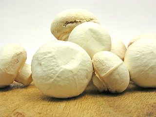 Image showing White  mushrooms on a brown wooden plate