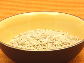 Image showing Brown rice in a bowl of ceramic on an orange background