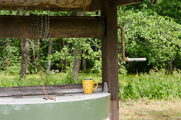 Image showing edge of old well pulley with chain and mottled cup 