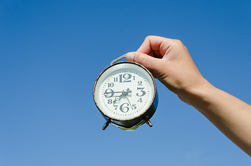 Image showing hand hold clock with big numeral on sky background 