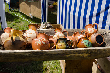 Image showing clay jugs lying in wooden trough at village market 