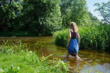 Image showing blonde girl blue mottled dress wade flowing river  