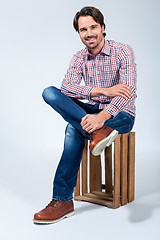 Image showing Handsome young man sitting on a wooden box