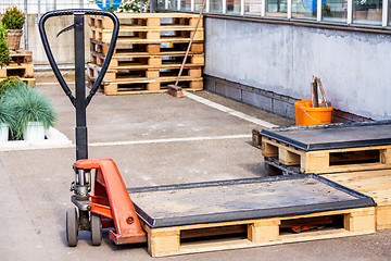 Image showing Small orange forklift parked at a warehouse