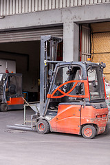 Image showing Small orange forklift parked at a warehouse