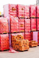 Image showing Red clay bricks stacked on pallets