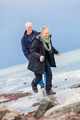 Image showing happy elderly senior couple walking on beach