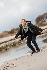 Image showing Happy senior woman frolicking on the beach