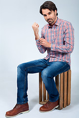 Image showing Handsome young man sitting on a wooden box