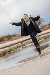 Image showing Happy senior woman frolicking on the beach