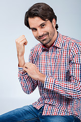 Image showing Handsome young man sitting on a wooden box