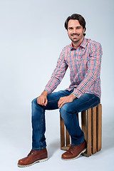 Image showing Handsome young man sitting on a wooden box