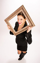 Image showing Brunette Woman in Business Suit and Boots Holds Ornate Frame Ove