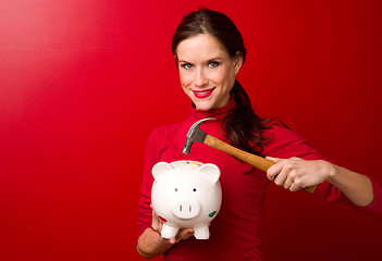 Image showing Woman in Red Starts to Break the Piggy Bank with Hammer