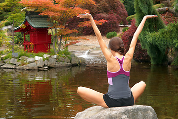 Image showing Woman Reaches for the Sky on Rock in Yoga Pond