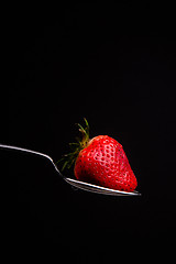 Image showing Red Raw Food Strawberry on a Silver Spoon on Black Background