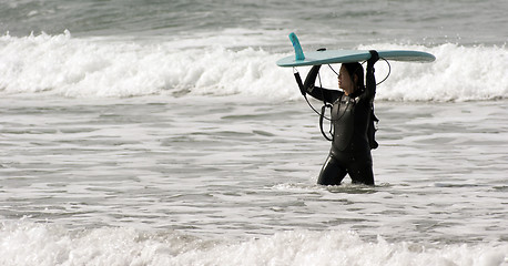 Image showing Serious Surf Boarder Female Carries her Surfboard through Surf