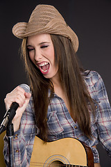 Image showing Cowgirl Singer Belts out Tune Yelling Singing into Microphone