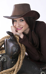 Image showing Cowgirl Relaxes in Brown Cowbooy Hat Leaning on Saddle With Rope