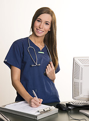 Image showing Beautiful Doctor Looks Up From Filling out Chart